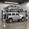 An AMGO 408-HP 4-Post Parking Lift, a black lift with two vehicles stacked on its platforms, a silver sedan on top and a silver Jeep on the bottom, inside a garage with concrete floors.
