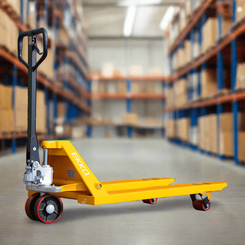 The yellow EKKO A25 Manual Pallet Jack with polyurethane wheels in a warehouse setting, with shelves of boxes blurred in the background.