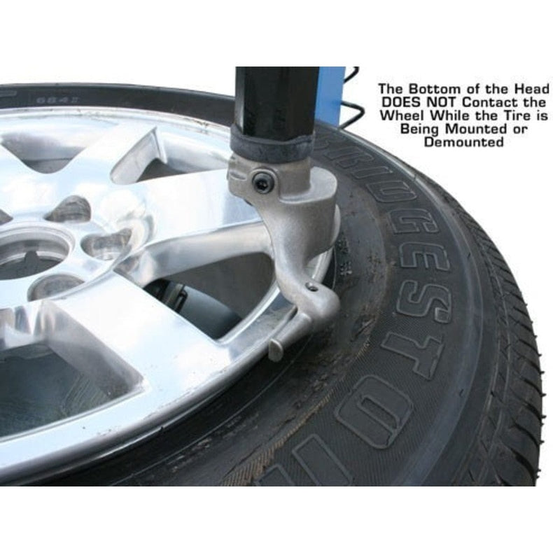 A close-up view of the mount/demount head on the Atlas TC229LH Rim Clamp Tire Changer with a wheel and tire, showing the note that the head should not contact the wheel while the tire is being mounted or demounted.