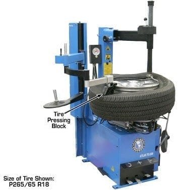 An Atlas TC229LH Rim Clamp Tire Changer with a passenger car tire mounted on the turntable. The image shows the bead breaker arm in action, pressing on the tire sidewall, with an overhead view of the tire pressure block.