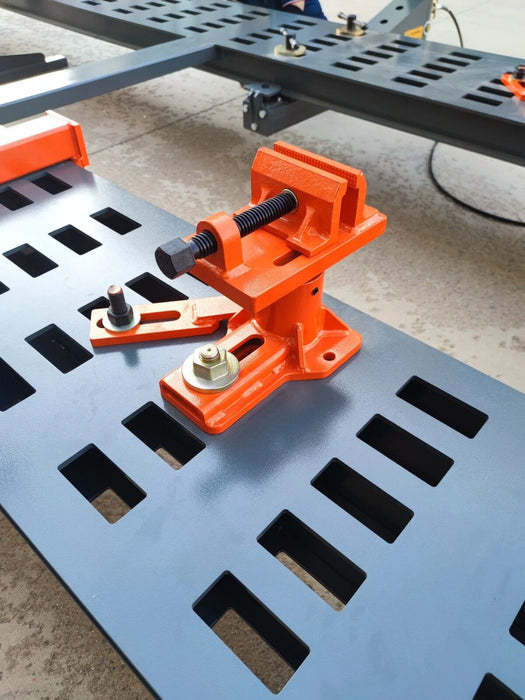 A close-up view of an orange and black Katool KT-299U main clamp, positioned on the machine's frame grid, highlighting the unique spiral movement design for precise and secure vehicle positioning.