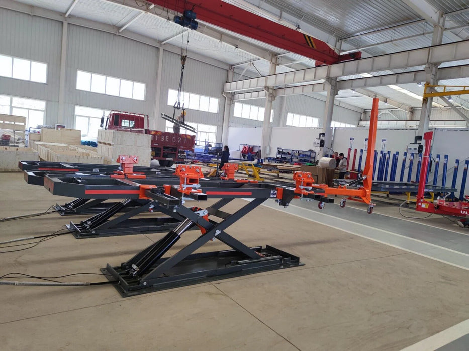 Two Katool KT-310 frame machines are shown in a warehouse, one with its scissor lift raised and the other lowered. The image displays the black scissor lift and orange crossbeam.