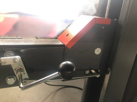 A close-up of the manual lock release lever on the Katool KT-4H110 4-post vehicle lift, with a red arrow graphic pointing to its function to lower the lift