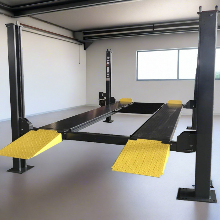 A black and yellow Katool 4-post car lift with an 8,500 lbs lifting capacity within a garage space