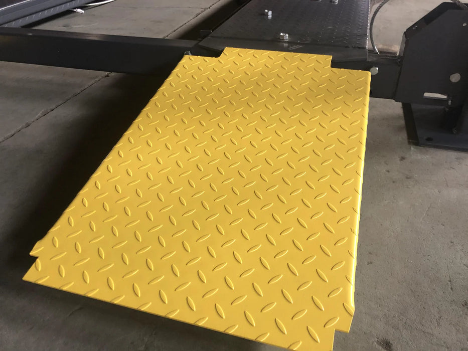 A close-up of the textured, yellow plate approach ramp for the car lift