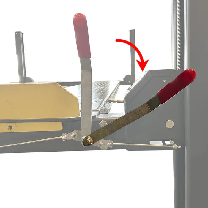 A close-up of the red manual safety lock release handle on the car lift's rail