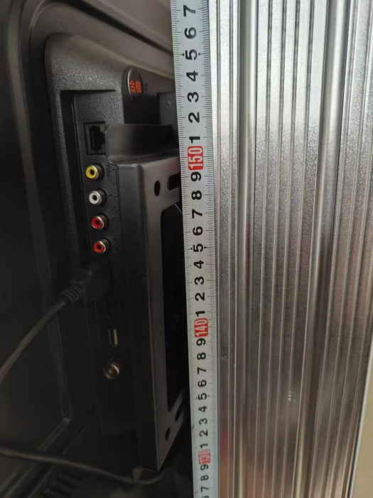A close-up of the back of a TV screen connected to the Katool KT-AV9 3D wheel aligner, showing different ports and a tape measure on the side.