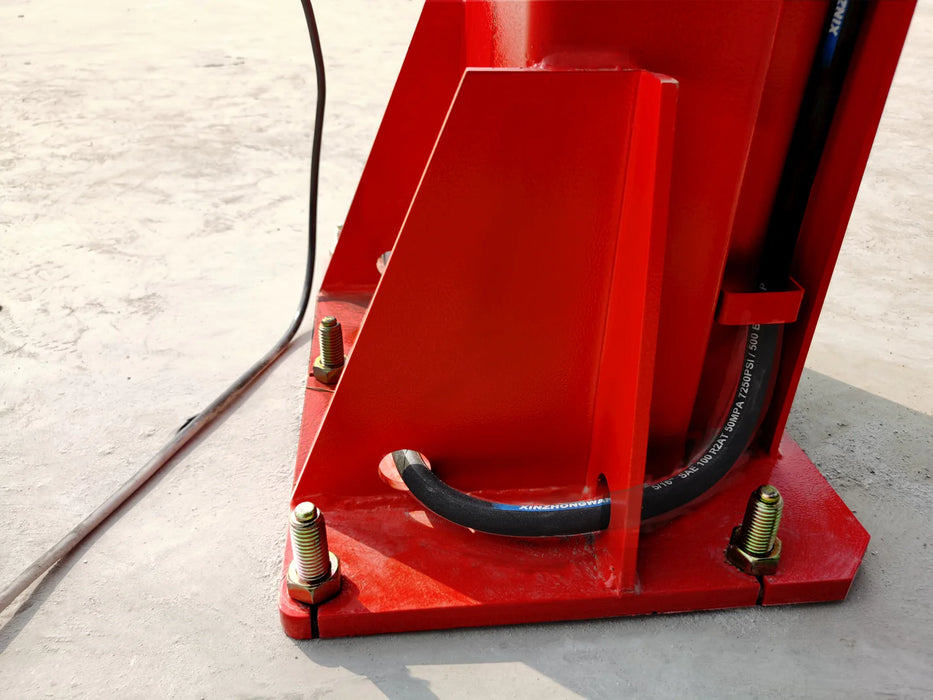A close-up of the red base plate of the Katool KT-M120 column, showing the bolts securing it to the ground and a black hydraulic hose with metal fittings running from the base.