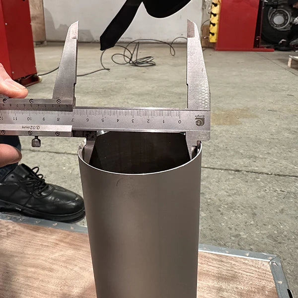 A close-up of a person's hand holding a caliper to measure the diameter of a part of the Katool KT-T830 tire changer. The measurement shows the internal diameter.