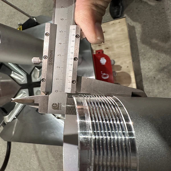A close-up shot of a person using a caliper to measure the outside of a grooved cylinder from the Katool KT-T830 tire changer.