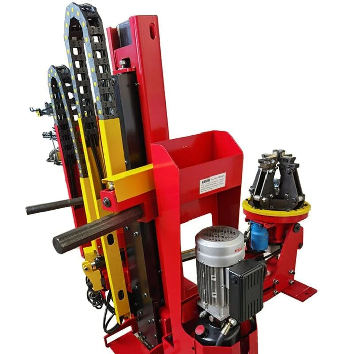 An angled view of the hydraulic motor and lifting mechanisms on the red and yellow Katool KT-TV910 truck tire changer. The intricate hydraulic system and heavy-duty components are visible.