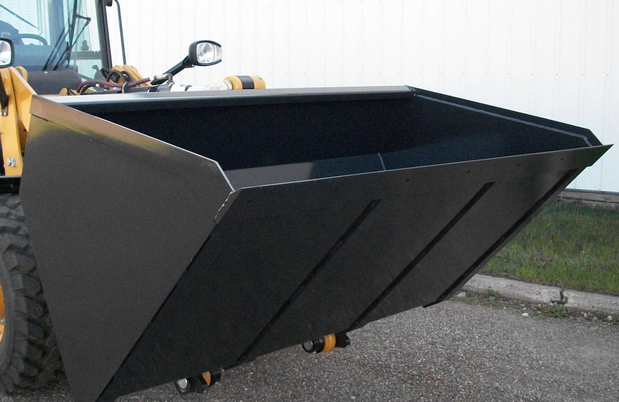 A front-side view of a black high-capacity fertilizer bucket mounted on a yellow John Deere 244 loader, showing its wide opening and heavy-duty construction in an outdoor environment.
