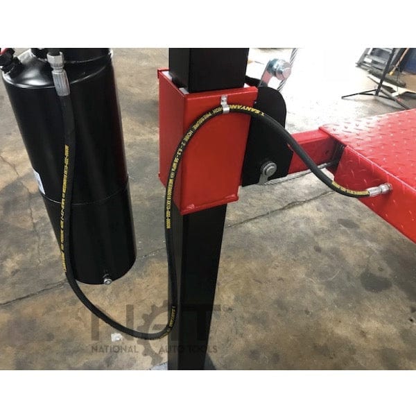A close-up view of the black hydraulic cylinder and a hose on the red NOS9000XLT lift, with a hose keeper bracket securing it to the post.
