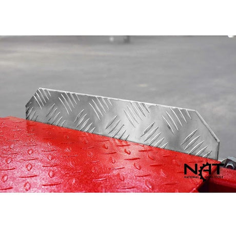 A close-up of the textured surface of the runway and a black wheel stop on the Triumph NOS9000 four-post lift.