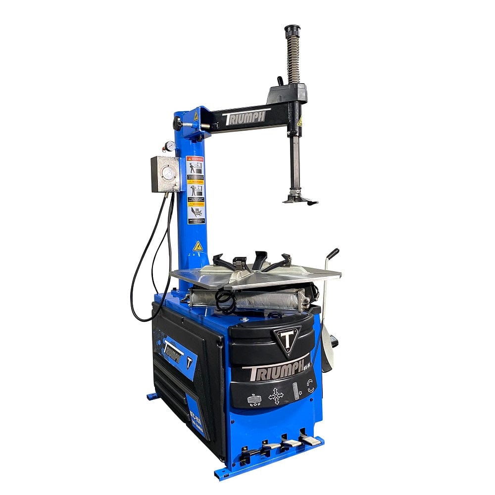 NTC-950_1.jpg: The Triumph NTC-950 tire changer, a large blue and black machine, is shown from a three-quarter view with a tire and wheel mounted for service. The tire changer is designed for commercial shops.
