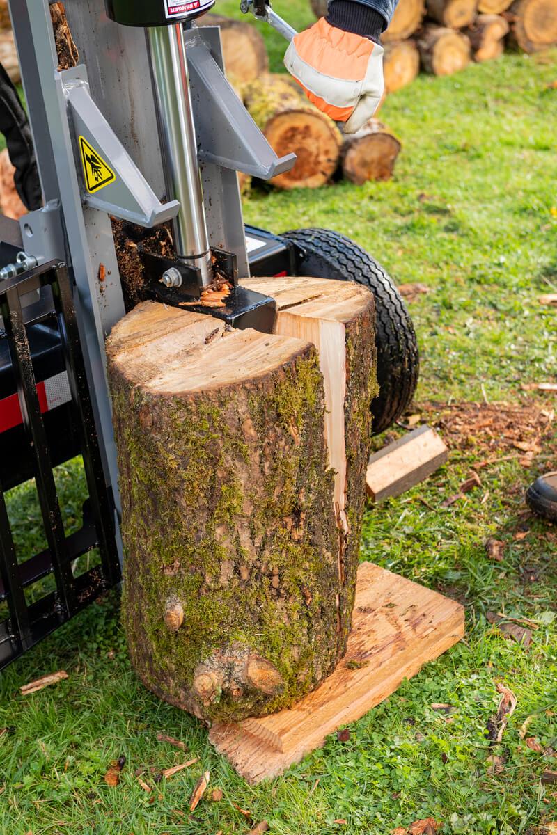 A large mossy log is being vertically split by the gray Oregon 3000 Series 30-ton log splitter on a splitting platform.