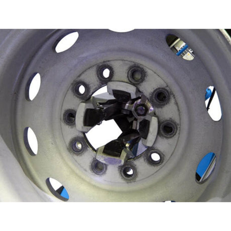 A close-up view of the center of a steel truck rim, showcasing the rim adapters attached to the Atlas TTC606 tire changer's internal clamping jaws.