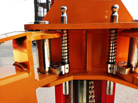 A detailed view of the top of the red and yellow Katool KT-M110 lift, showing the heavy-duty springs and bolts that secure the components.