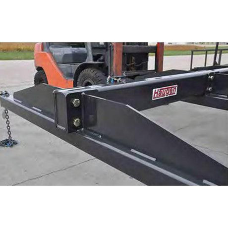 A close-up view of a black HAUSEN Forklift Mesh Handler attached to the forks of an orange forklift. The heavy-duty steel frame is visible.