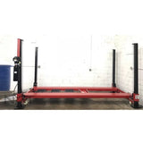 A side view of the red Triumph NOS9000 four-post lift, showing the side profile of the ramps and posts.