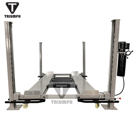 A front view of the light grey Triumph NSS-8 Four-Post Lift, showing the runways with three black drip trays placed in the center. A jack tray is positioned at the back of the runways.