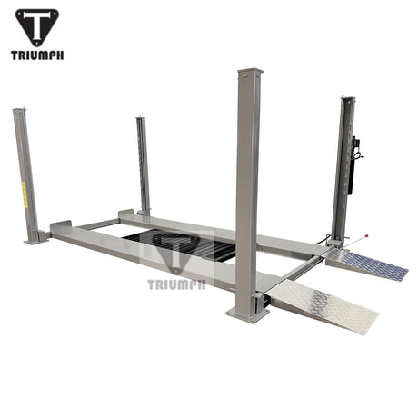 A side view of the light grey Triumph NSS-8 Four-Post Lift, showing the height of the posts and the attached diamond plate runways. The Triumph logo is visible on the posts and center runway.