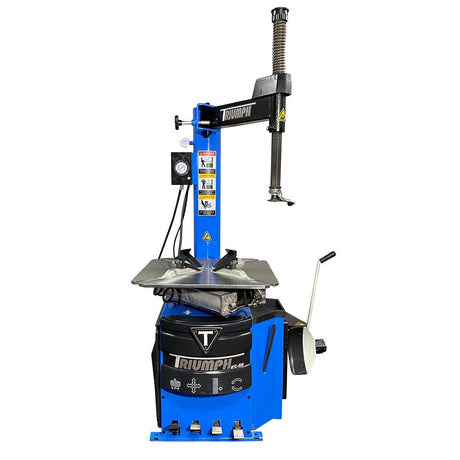  A close-up front view of the Triumph NTC-950 tire changer, highlighting its pneumatic foot pedals, control valves, and tire bead breaker.

