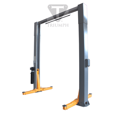 A three-quarter view of the Triumph NTO-15 15,000 lb Two Post Auto Lift, showing its grey and orange-yellow frame with the overhead bar and lift arms lowered. The base plates are visible at the bottom of each post.