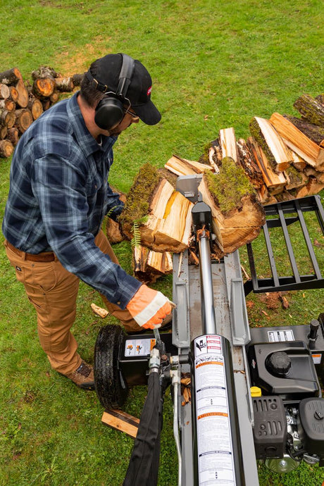 A person operating the Oregon 3000 Series 30-ton log splitter in the horizontal position, splitting logs in a grassy outdoor area.